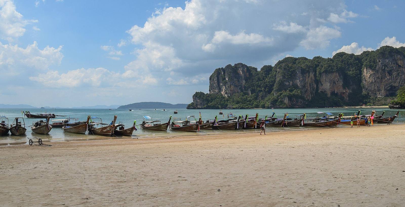 Longtail boats lined up on Railay West beach below limestone cliffs