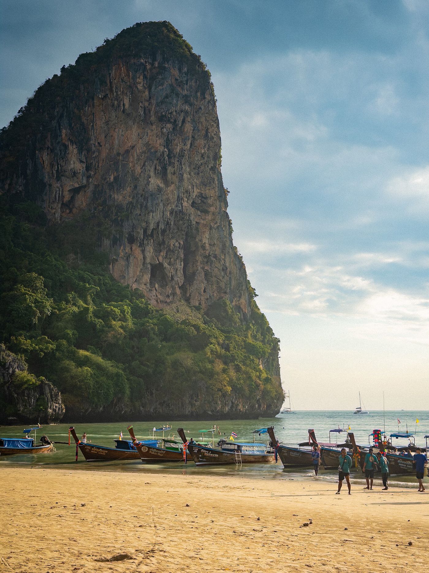 Longtail boats pulled up on the sand at Railay West below a limestone cliff